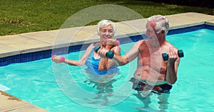 Senior couple exercising with dumbbells in the pool