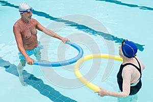 Senior couple exercising with pool noodle
