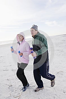 Senior couple exercising, running on beach