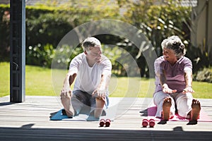 Senior couple exercising together on mat at porch