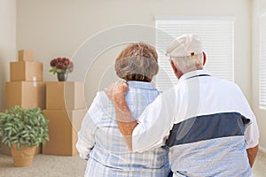 Senior Couple Facing Empty Room with Packed Moving Boxes and Pot