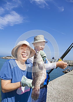 senior couple fishing and showing big grouper fish