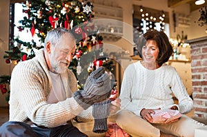 Senior couple in front of Christmas tree enjoying presents.