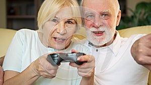 Senior couple gamers playing video games at home. Players with remote controller of game console