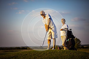 Senior couple on golf court. Focus is on man.