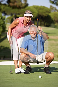 Senior Couple Golfing On Golf Course