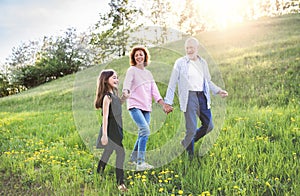 Senior couple with grandaughter outside in spring nature, walking.