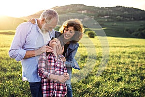 Senior couple with granddaughter standing outside in spring nature. Copy space.