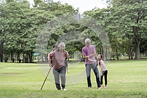 Senior couple with granddaughter on a walk outside in nature. Seniors with granddaughter, summer day. People walking on grass