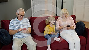Senior couple grandparents with child girl grandchildren using digital tablet, mobile phone