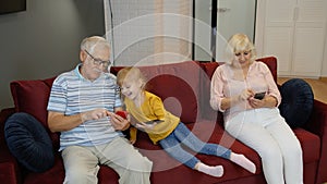 Senior couple grandparents with child girl grandchildren using digital tablet, mobile phone