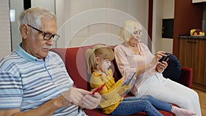 Senior couple grandparents with child girl granddaughter using digital tablet, mobile phone