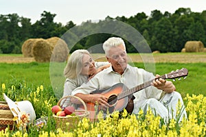 Senior couple with guitar at summer field