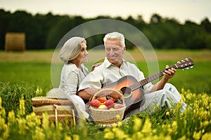 Senior couple with guitar at summer field