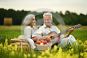 Senior couple with guitar at summer field