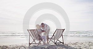 Senior couple, happy and hug on beach chair for care support, talking and holding hands on holiday. Mature man, woman or