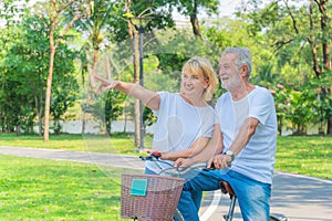Senior couple happy together riding bicycle outdoor in park in summer