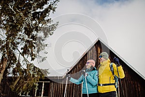 Senior couple having break during skying, next forest cottage.