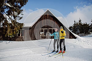 Senior couple having break during skying, next forest cottage.