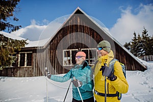 Senior couple having break during skying, next forest cottage.