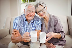 Senior couple having coffee in living room