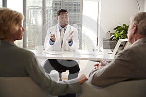 Senior Couple Having Consultation With Male Doctor In Hospital Office