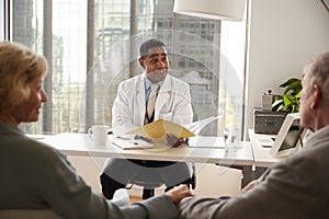 Senior Couple Having Consultation With Male Doctor In Hospital Office