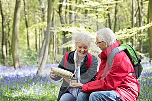 Senior Couple Having Drink From Flask On Walk Through Bluebell W