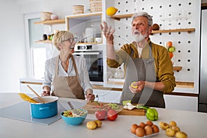 Senior couple having fun, cooking together in home kitchen