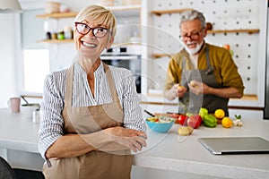 Senior couple having fun in kitchen with healthy food at home