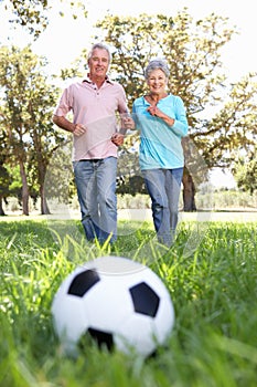 Senior couple having fun playing football