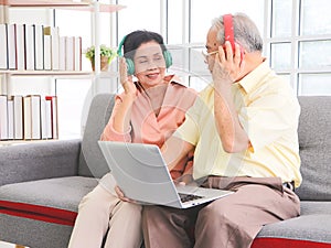 Senior couple having goodtime together , listen to the music from headphones with computer laptop on lap. Elderly lifestyle