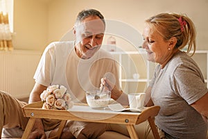 Senior couple having healthy breakfast together in bed.