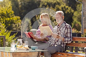 Senior couple having and outdoor breakfast and reading in the backyard