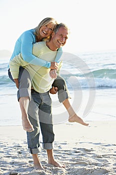 Senior Couple Having Piggy Bck On Sandy Beach