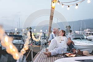 Senior couple having tender moment on boat while drinking champagne and eating fruits - Focus on faces