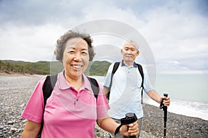 senior couple hiking on the coast beach