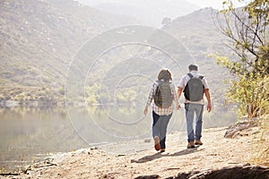 Senior couple hiking by a mountain lake, back view