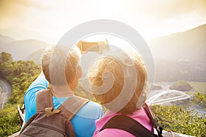 Senior couple hiking on mountains and taking selfies photo