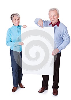 Senior couple holding blank placard