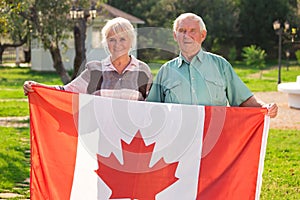 Senior couple holding Canadian flag.