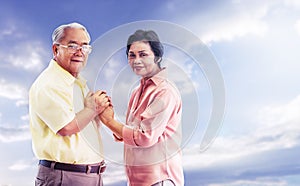 Senior couple holding hands for love and togetherness concept with blue sky background