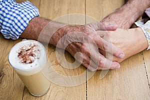 Senior couple holding hands in outdoor cafÃ©