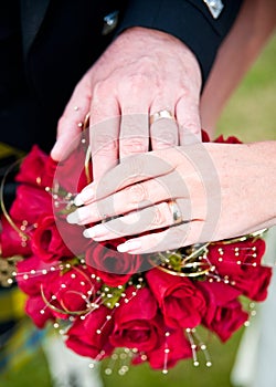 Senior Couple Holding Hands over a wedding red rose bouquet