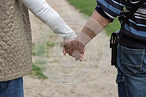 Senior couple holding hands together and walking in spring garden road. Elderly marriage in love. Relationship concept.