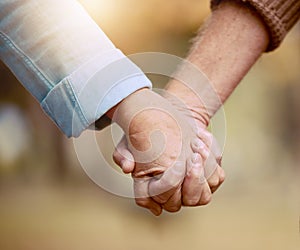 Senior couple, holding hands and walking in nature to bond in the countryside for love, care and affection. Retirement
