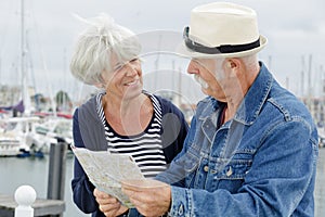 senior couple holding map by harbour