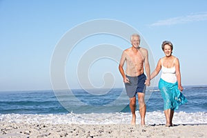 Senior Couple On Holiday Running Along Beach
