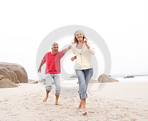 Senior Couple On Holiday Running Along Beach