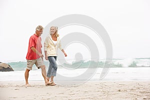 Senior Couple On Holiday Running Along Beach